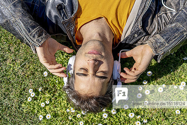 Man lying on flower meadow with headphones