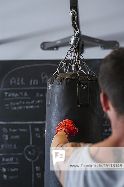 Young man boxing against punch bag