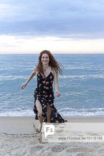 Porträt einer glücklichen jungen Frau  die am Strand läuft