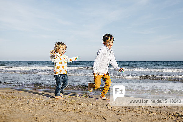Junge und seine kleine Schwester spielen am Strand