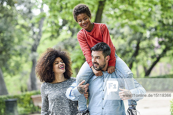 Glückliche Familie beim Spaziergang im Park  Vater trägt Sohn huckepack