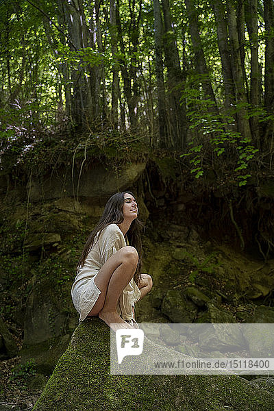 Junge Frau sitzt auf einem Felsen im Wald  Garrotxa  Spanien