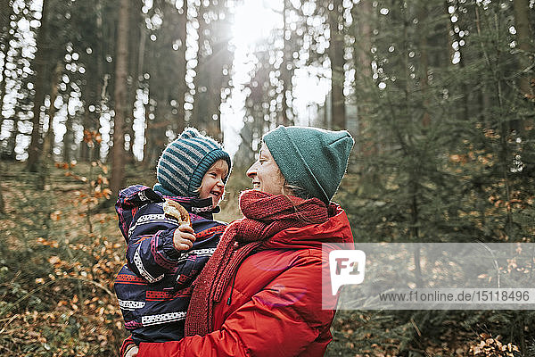 Mother carrying happy little daughter in autumnal forest