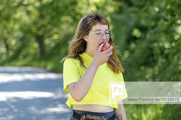 Porträt einer jungen Frau mit Brille  die einen Apfel hält