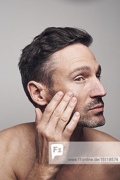 Mann, der sein Gesicht eincremt