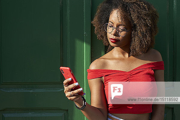 Frau in Rot prüft ihr Telefon