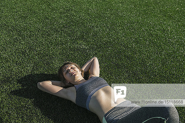 Sportlerin entspannt sich  liegt nach dem Training auf dem Rasen