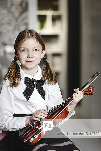 Portrait of a smiling girl with a violin at home