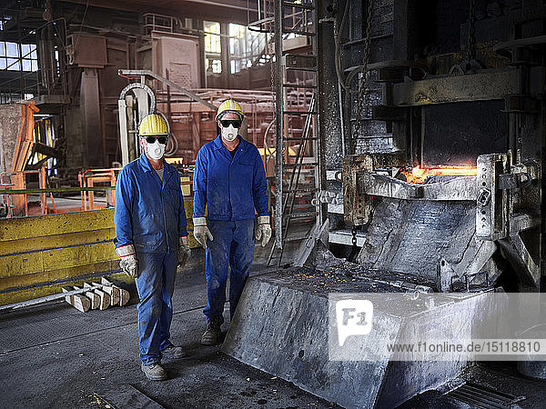 Industry  Smeltery: Workers in front of blast furnace with helmet and dust mask