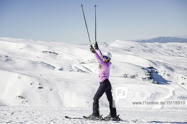 Glückliche Frau hebt ihre Skistöcke in verschneiter Landschaft in Sierra Nevada  Andalusien  Spanien