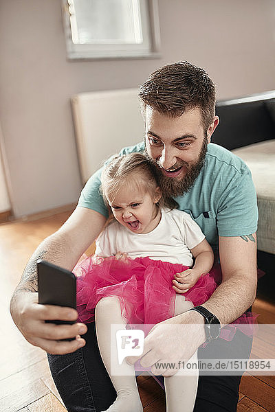 Vater und Tochter nehmen ein Selfie  Mädchen trägt rosa Tutu
