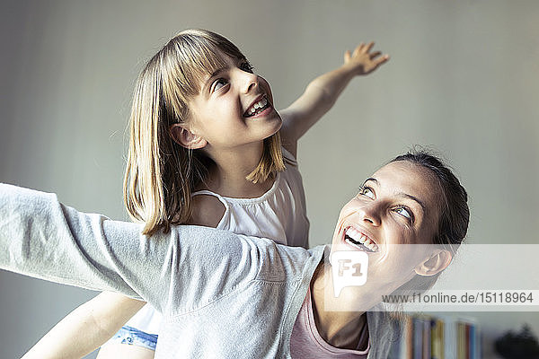 Mutter und Tochter spielen zu Hause und tun so  als würden sie fliegen