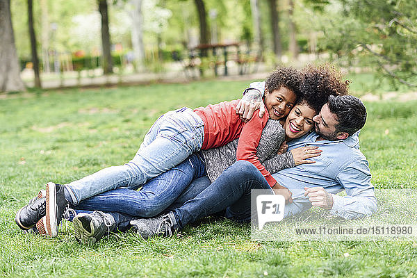 Happy family embracing  lying on grass in a park