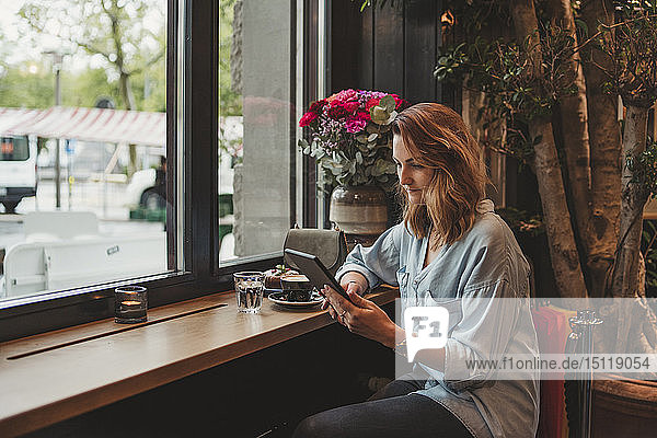 Junge Frau mit einem E-Book in einem Cafe