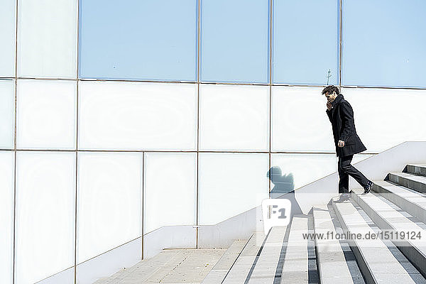 Businessman on cell phone walking down stairs in the city