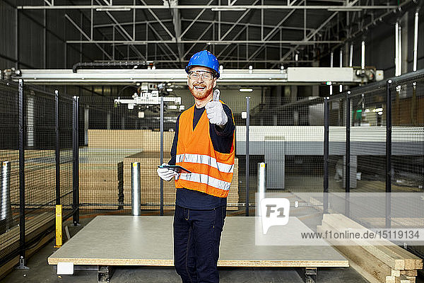 Portrait of happy worker with tablet in factory warehouse