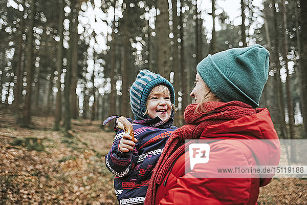 Mutter trägt glückliche kleine Tochter im Herbstwald