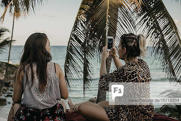 Mexiko  Quintana Roo  Tulum  zwei junge Frauen mit Handy am Strand