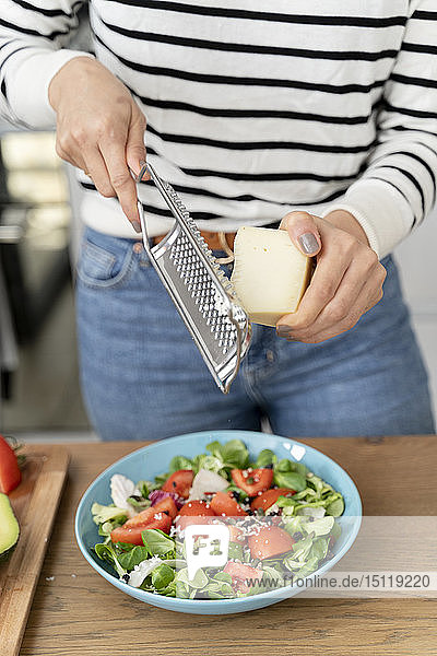 Woman standing in kitchen  preparing salad for lunch