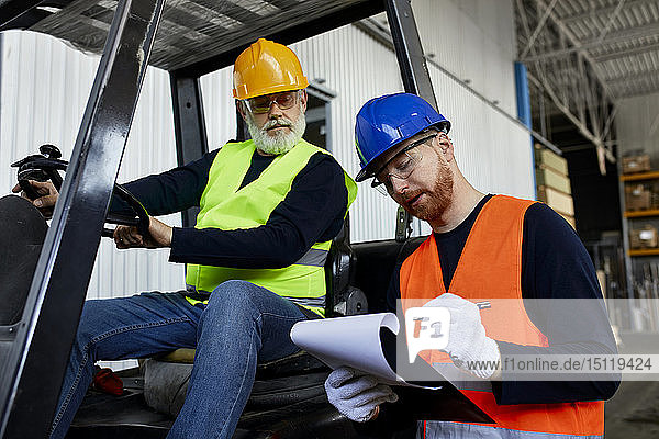 Man talking to worker on forklift in factory
