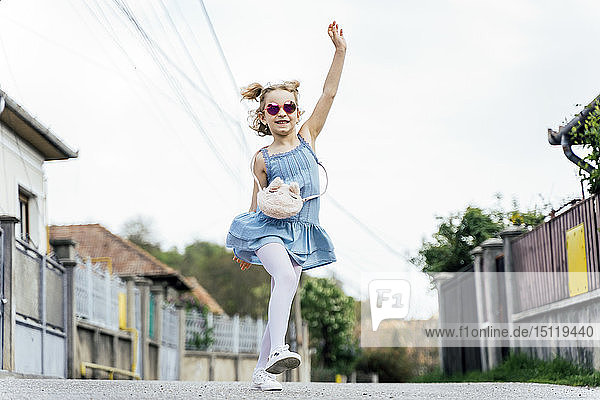 Glückliches kleines Mädchen tanzt auf der Straße