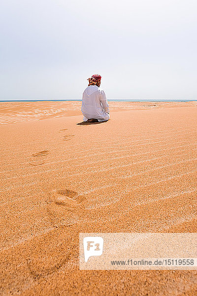 Beduine in Nationaltracht betend in der Wüste  Rückansicht  Wahiba Sands  Oman