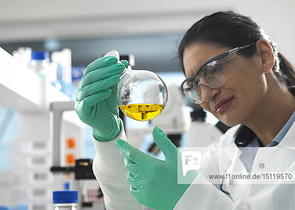 Biotech-Forschung  Wissenschaftlerin wirbelt während eines Experiments eine chemische Formel in einem Laborkolben herum