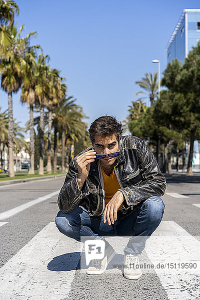 Spain  Barcelona  man crouching on zebra crossing