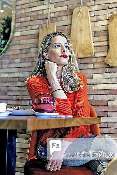Frau  die in einem Café am Tisch sitzt
