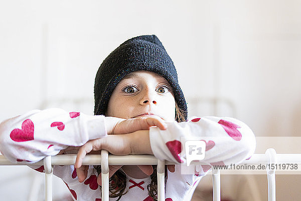 Porträt eines kleinen Mädchens im Bett mit Mütze und Pyjama