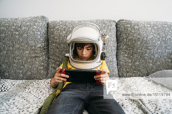Junge  der ein Videospiel auf einer Spielkonsole spielt und einen Weltraumhut trägt