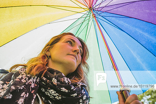 Junge Frau unter buntem Regenschirm