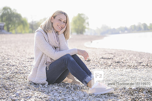 Porträt einer lächelnden  reifen Frau  die am Flussufer sitzt