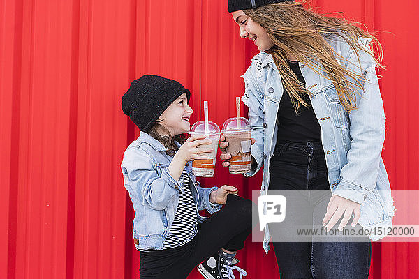 Teenagerin und kleine Schwester stoßen mit Getränken an