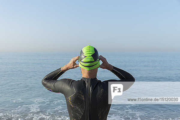 Triathlet  der sich zum Schwimmen vorbereitet  Schwimmkappe und Schutzbrille aufsetzen  Rückansicht