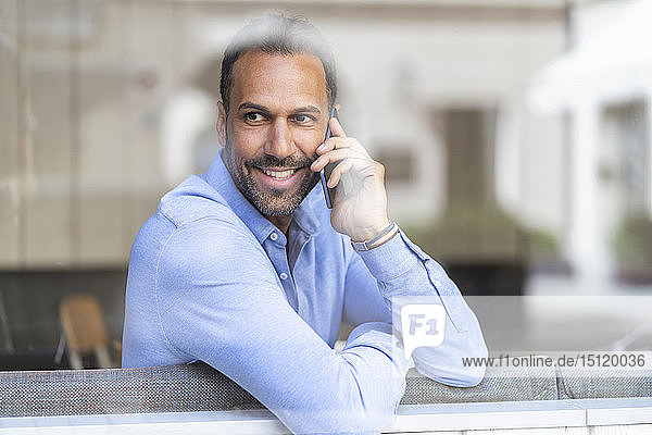 Smiling businessman on cell phone behind windowpane