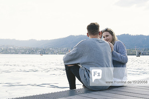 Young couple sitting on jetty at Lake Zurich  Zurich  Switzerland