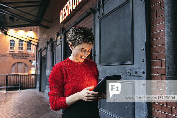 Germany  Berlin  smiling restaurant manager using digital tablet outdoors