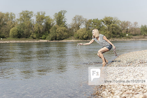Glückliche reife Frau planscht in einem Fluss