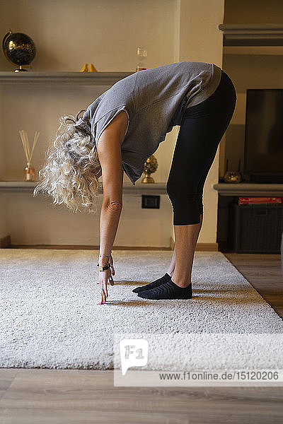 Reife Frau macht Yoga-Übung im Wohnzimmer