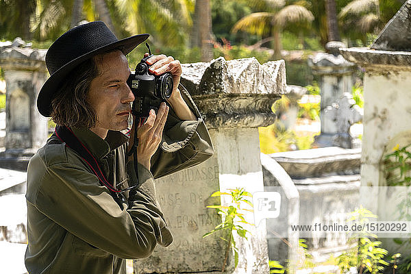 Seychellen  La Digue  Mann fotografiert Grabsteine auf einem alten Friedhof