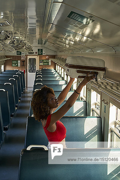 Junge Frau stellt ihren Koffer in einen Zug