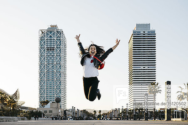 Spanien  Barcelona  Junge Frau springt  Hochhäuser im Hintergrund