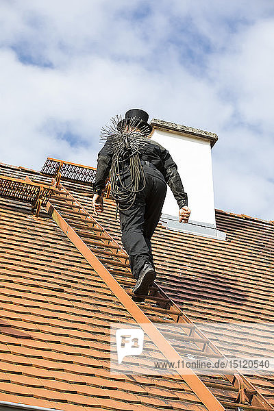 Schornsteinfeger klettert auf Hausdach