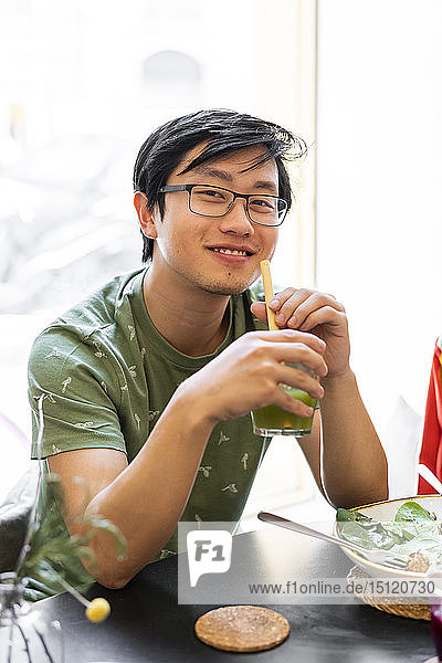 Porträt eines lächelnden Mannes  der in einem Restaurant bei einem gesunden Mittagessen am Tisch sitzt