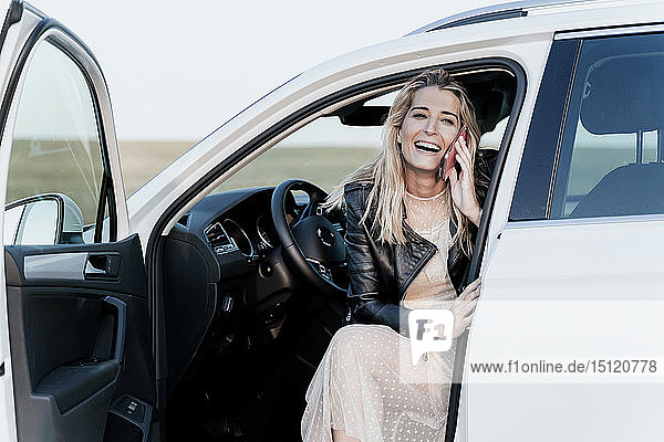 Blond woman using smartphone  sitting in white car