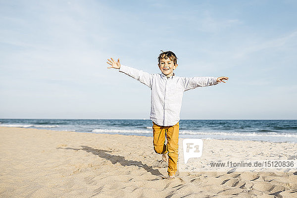 Porträt eines glücklichen kleinen Jungen  der am Strand läuft