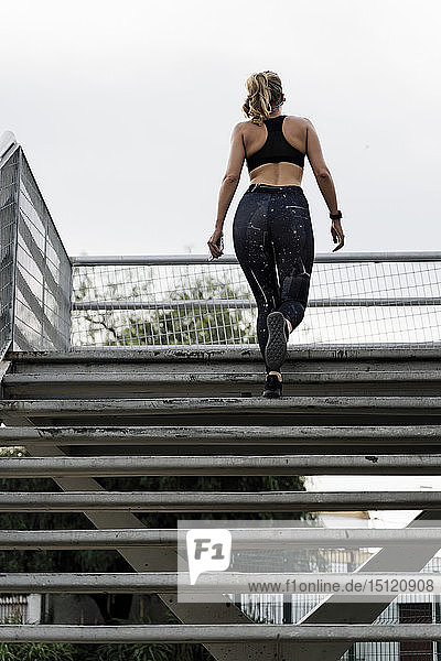 Sportliche Frau beim Treppensteigen auf einer Brücke  Rückansicht