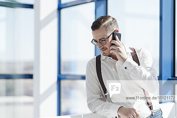 Geschäftsmann telefoniert am Fenster im modernen Büro per Handy