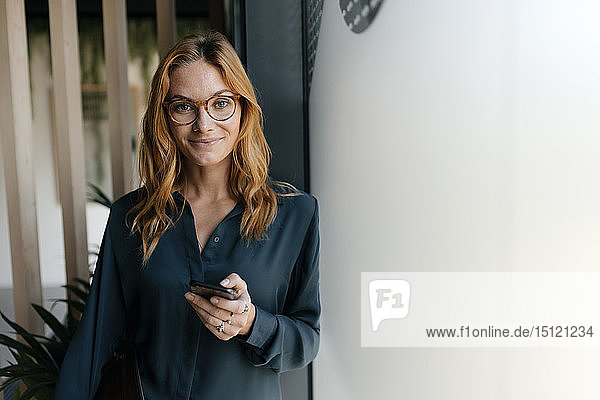 Portrait of confident businesswoman holding cell phone
